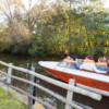 people sitting in a boat with life jackets on in the river