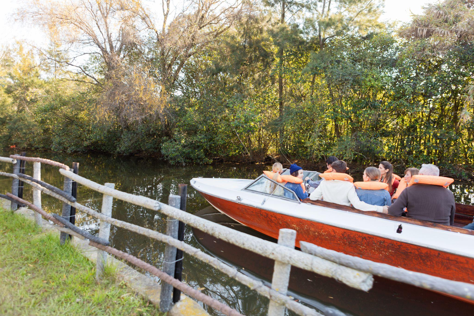 people sitting in a boat with life jackets on in the river